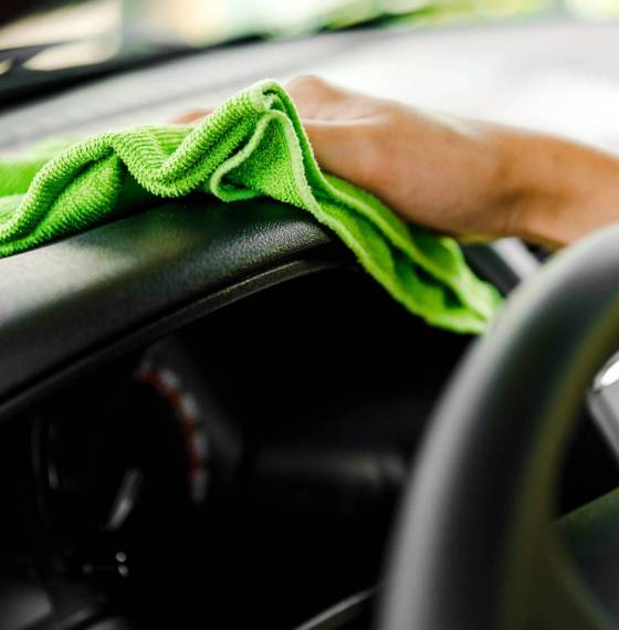 Hand with microfiber cloth cleaning car.