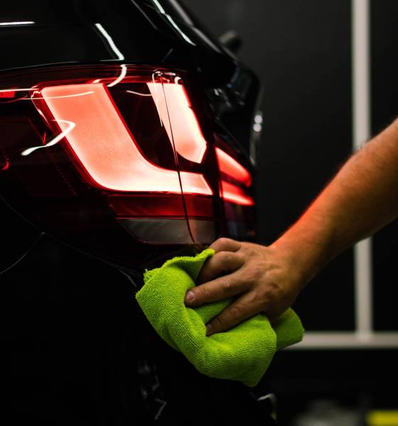 A selective focus shot of a man cleaning car's back headlight with a microfiber cloth